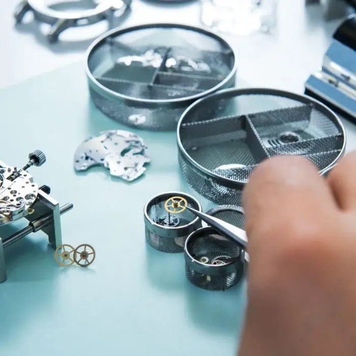 Watchmaker inspecting movement parts